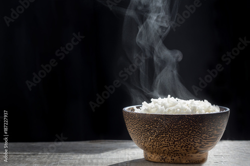 Cooked rice with steam in wooden bowl on dark background,hot cooked rice in bowl selective focus,soft focus photo