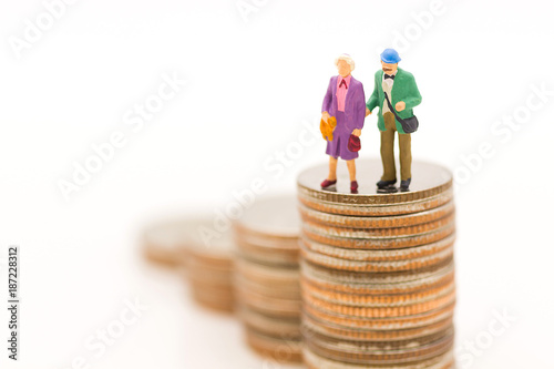 Miniature people, Old couple figure standing on top of stack coins using as background retirement planning, Life insurance concept.