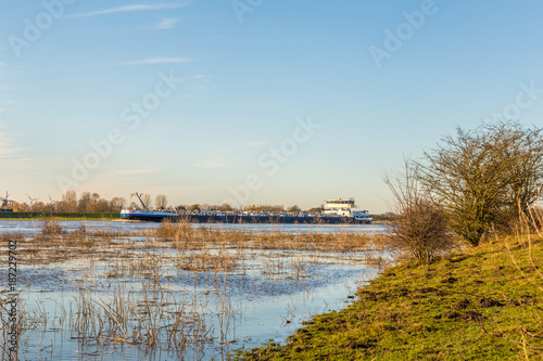 Landscape with flooded river Rhine and oil tanker near Arnhem in the Netherlands