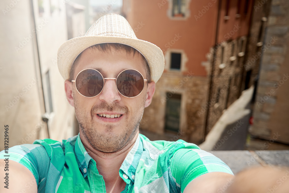Man in sunhat travelling by European town is making a selfie. Man in sunhat travelling by European town is making a selfie.