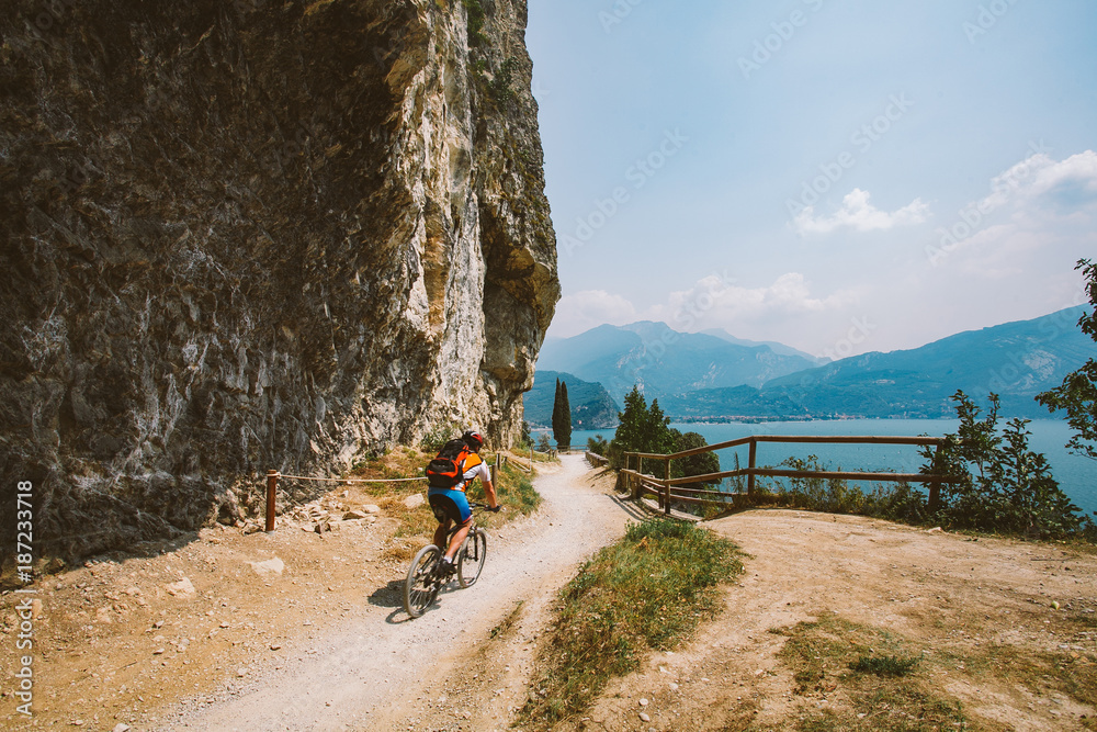 Fototapeta premium man cyclist on a mountain bike riding on a gravel bike route at a height near the Lago di Garda in summer in Italy