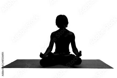 Attractive tanned fit young Caucasian businessman sitting cross legged on mat  keeping yes closed and holding hands on his knees  relaxing after hard working day at office. Yoga and meditation