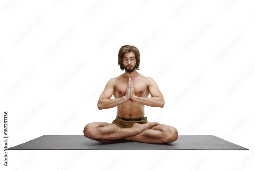 Sporty beautiful young man practicing yoga, sitting cross-legged in Adho  Mukha Padmasana, bending forward in variation of Lotus Pose on white  background. Stock Photo | Adobe Stock