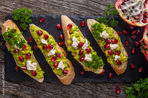 Toast with avocado and pomegranate on wooden table