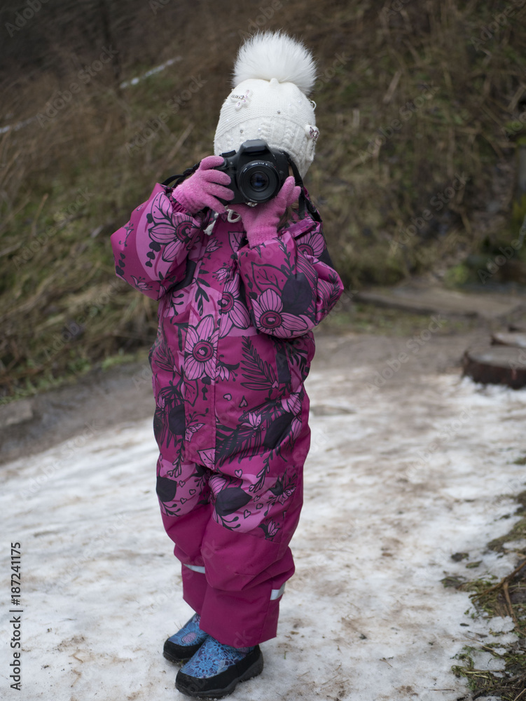 little girl photographer takes pictures in winter with a professional camera in a fur coat
