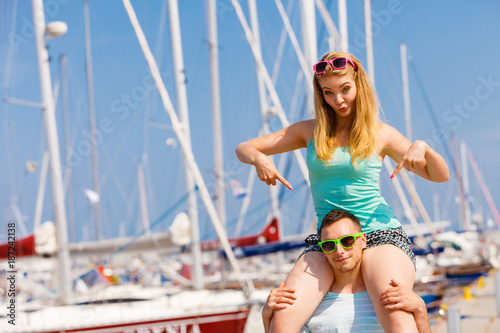 Man giving girlfriend piggyback ride on marina