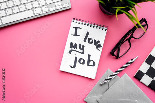 Find dream job. Handwritten motto I love my job in notebook on office desk on pink background top view copyspace photo