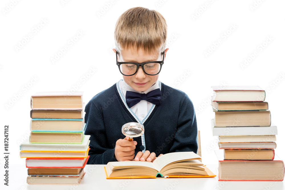 smart boy with glasses with a magnifying glass is considering the text of the book, portrait isolated smart boy with glasses with a magnifying glass is considering the text of the book, portrait isolated