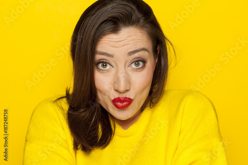 beautiful sexy woman in a yellow blouse with kissing gesture on a yellow background
