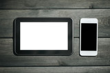 White mobile phone with black empty copy space and black tablet with white empty copy space on wooden desks background.
