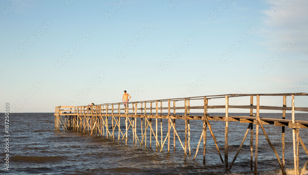 man walking on a high wooden pier over the lake