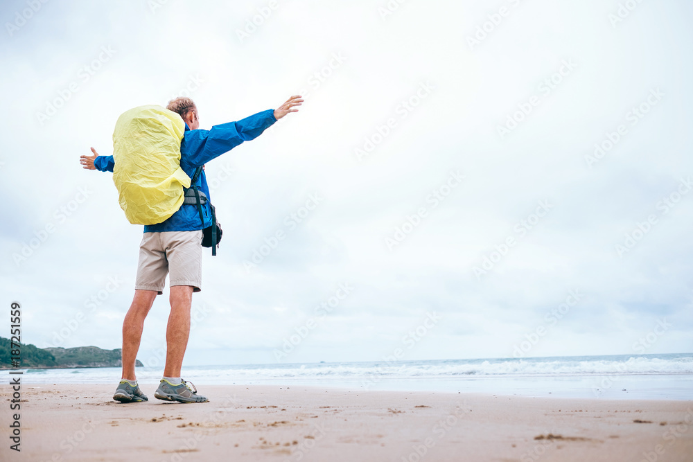 Backpacker traveler enjoy with ocean energy on the empty beach in rainy day