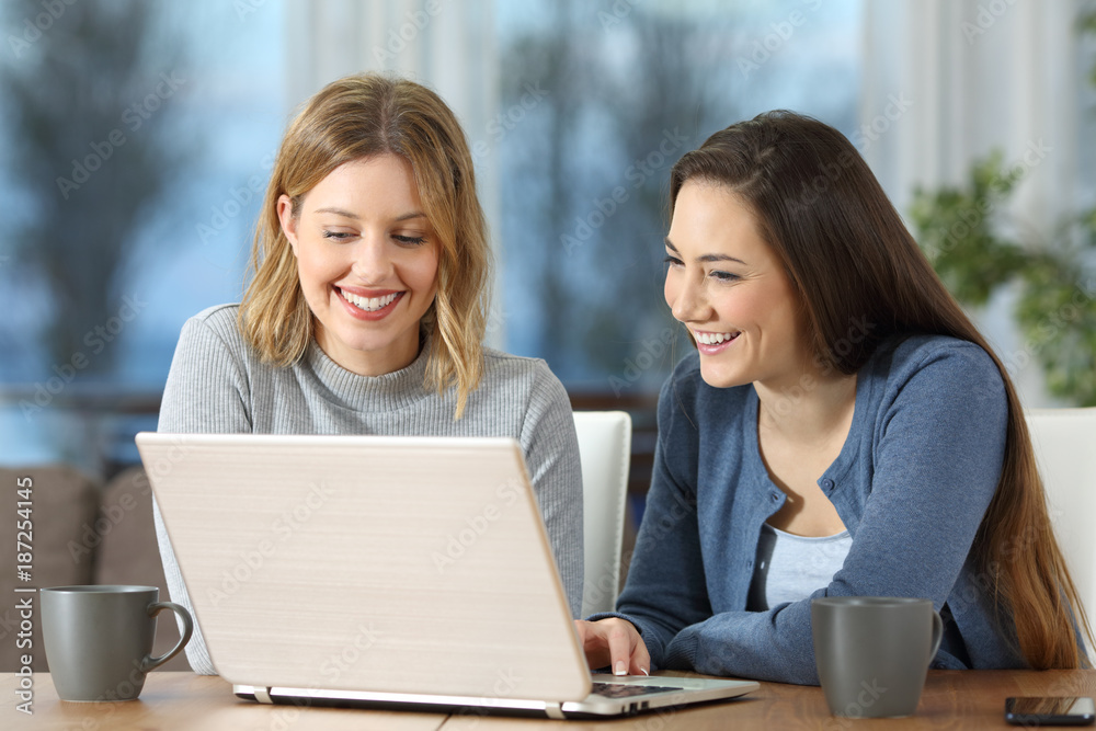 Women watching media content on line in a laptop at home Women watching media content on line in a laptop at home