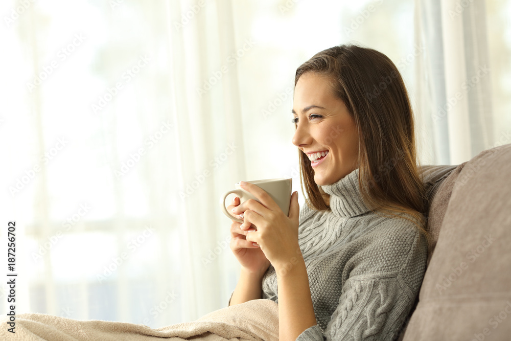Pensive woman holding a coffee mug relaxing at home Pensive woman holding a coffee mug relaxing at home