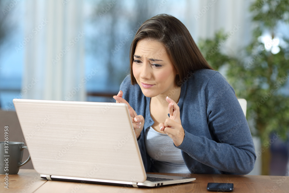 Woman crossing fingers checking on line content Woman crossing fingers checking on line content