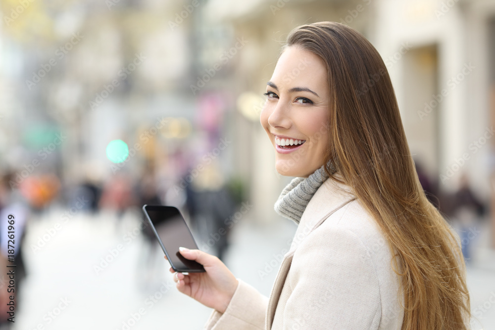 Woman using a phone and looking at camera in winter Woman using a phone and looking at camera in winter
