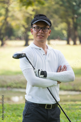 Portrait of asian young male golfer with golf club on the golf course.