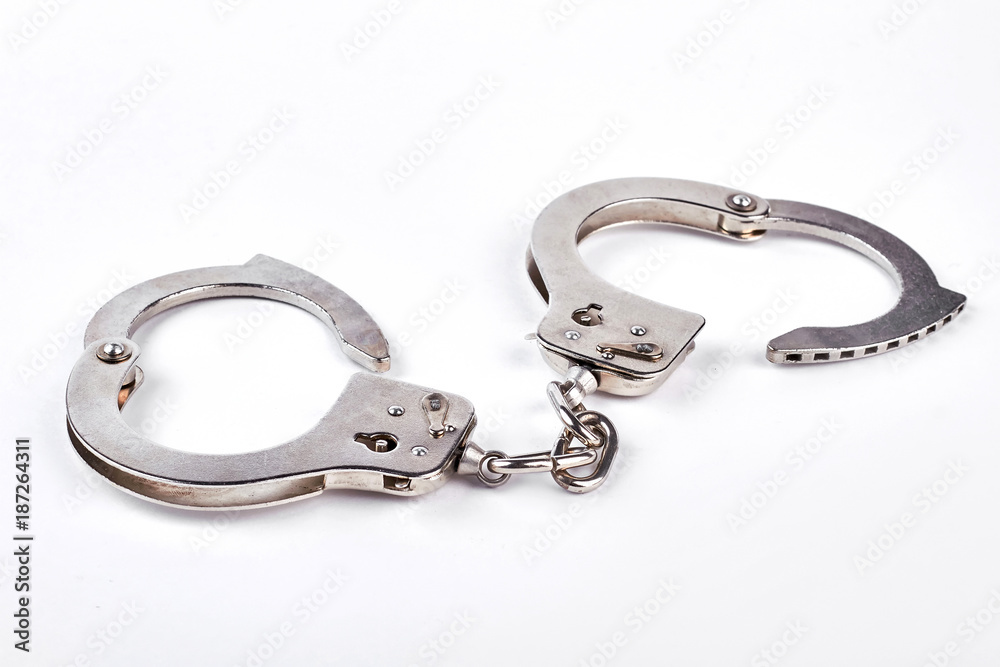 Pair of metal handcuffs over white background. Silver handcuffs isolated on white. Pair of metal handcuffs over white background. Silver handcuffs isolated on white.
