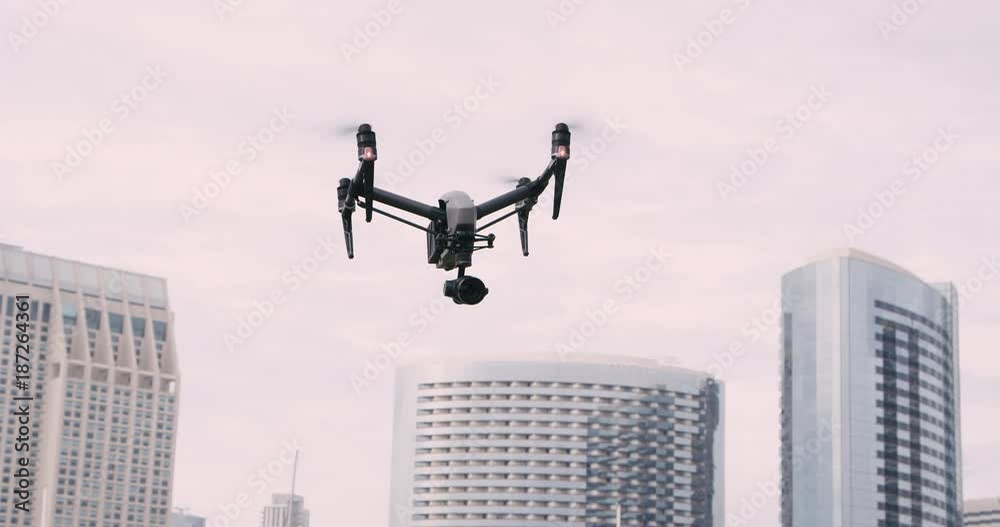 Quadcopter drone with camera on gimbal flying in the city sky, shot in slow motion 