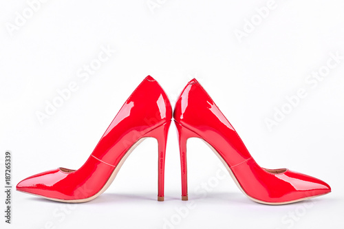 Classic red high-heeled female shoes. Pair of red lacquered stilettos isolated on white background. Woman modern style.