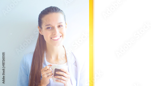 Attractive woman sitting at desk in office, working with laptop , having takeaway coffee