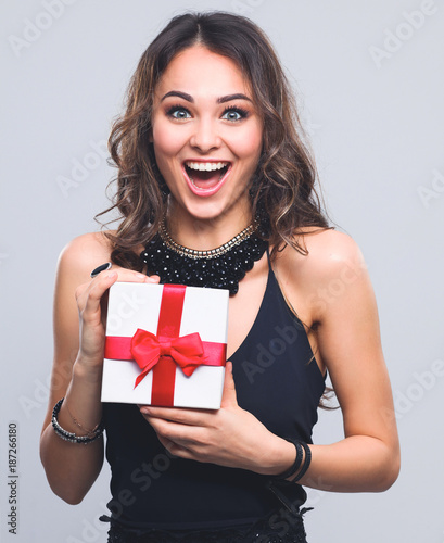 Young woman happy smile hold gift box in hands, isolated over grey background
