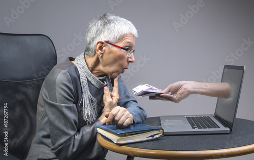 Senior old lady being lured into an online scam that promises easy money, money fraud concept photo
