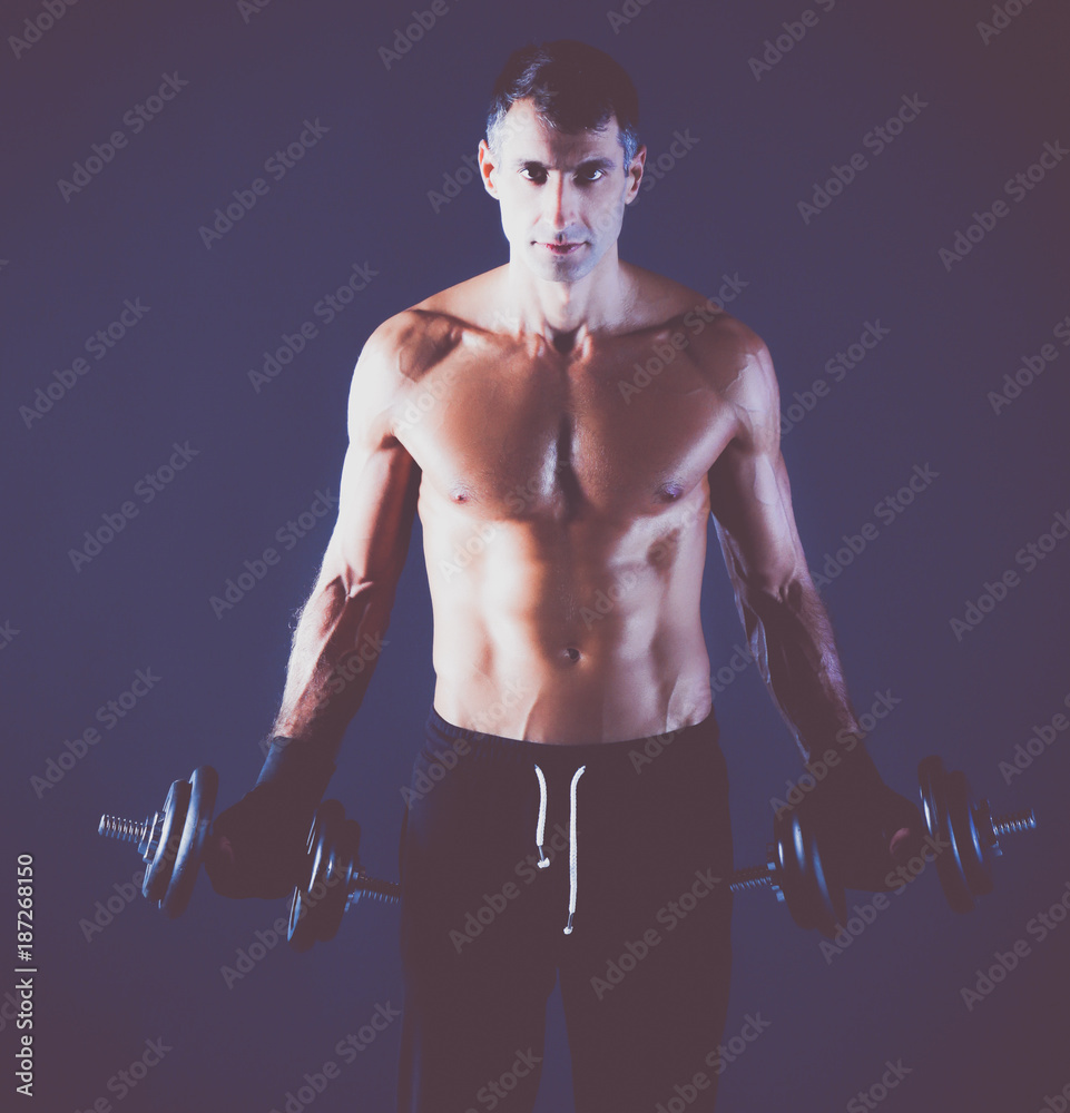 Handsome muscular man working out with dumbbells