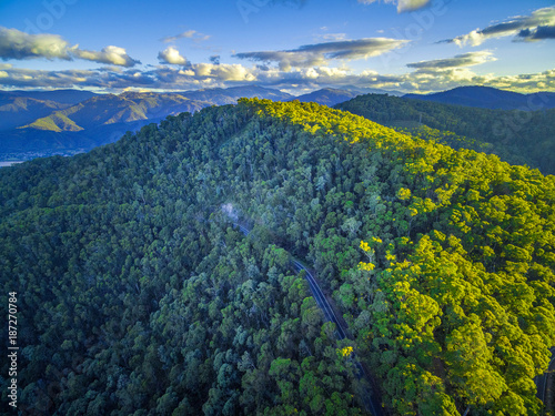 Aerial view of rural road winding through native Australian forest and mountains at sunset photo