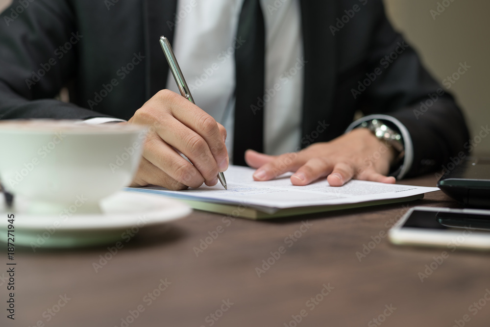 Close up businessman is signing a contract, business contract details at coffee shop Close up businessman is signing a contract, business contract details at coffee shop