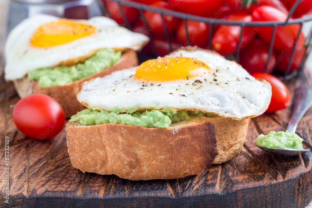 Open sandwiches with mashed avocado and fried egg on bread, horizontal
