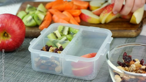 Woman hand put healthy fruit and nut snacks into the lunch box