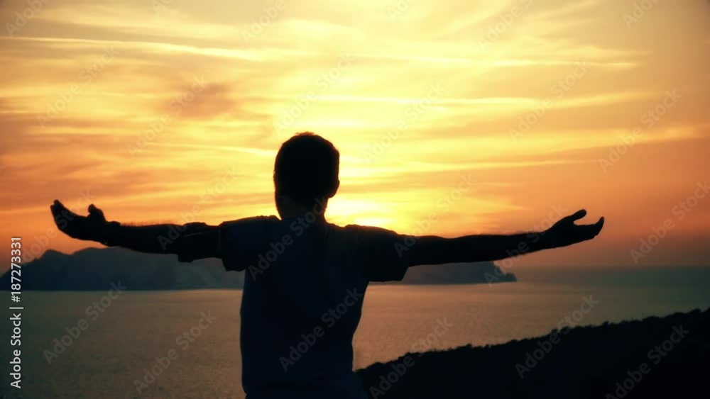 Silhouette of active young man stretching doing yoga exercise on top of a mountain cliff on ponza island at sunset with the sea landscape on the background slow motion Silhouette of active young man stretching doing yoga exercise on top of a mountain cliff on ponza island at sunset with the sea landscape on the background slow motion