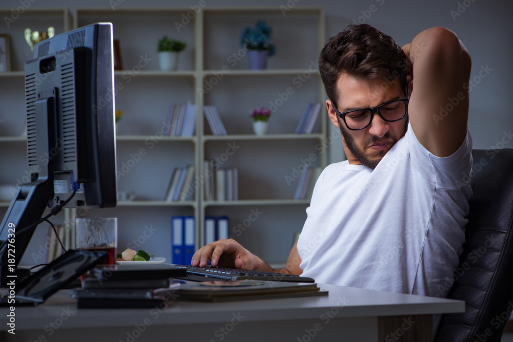 Young man staying late in office to do overtime work