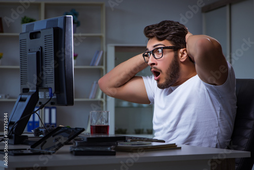 Billede på lærred Young man staying late in office to do overtime work