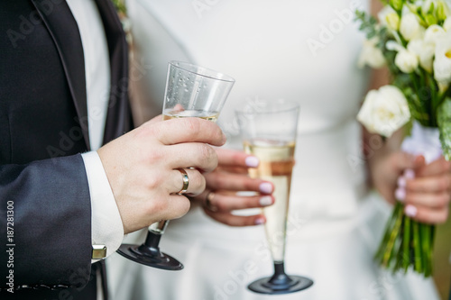 The groom holds a glass of champagne next to the bride