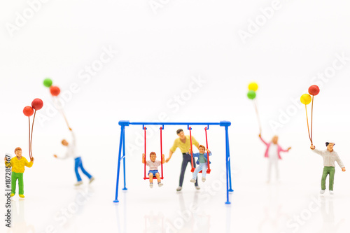 Miniature people : father swing cradle with children, and childrens play balloon together wiht fun, using as background International day of families concept.