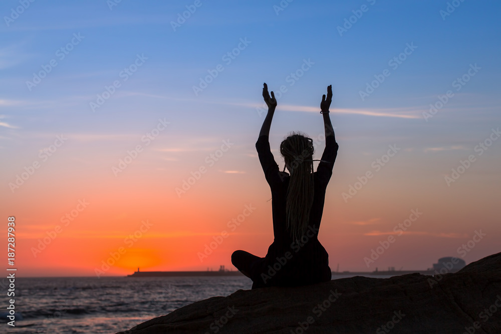 Silhouette of yoga meditation woman on the ocean during amazing sunset.