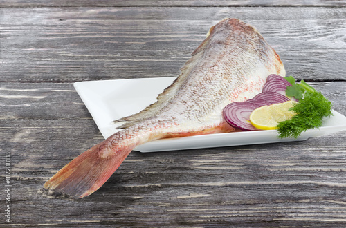 Uncooked red cod with dill, sliced lemon and onion closeup photo