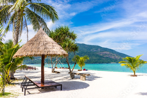 Fototapeta Naklejka Na Ścianę i Meble -  Beautiful tropical white beach with coconut palm trees and beach chairs. Holiday and vacation concept