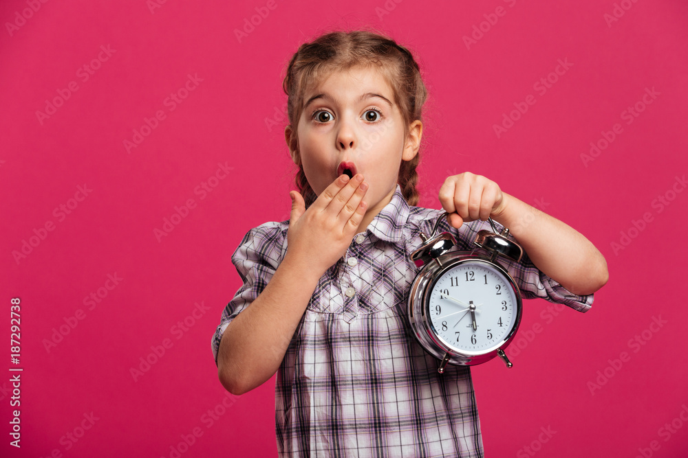 Shocked little girl child holding clock alarm. Shocked little girl child holding clock alarm.