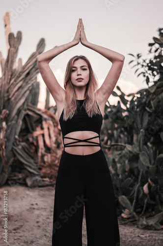 Beautiful blond woman in black jumpsuit posing near cactus. Boho and hippie style. Freedom concept