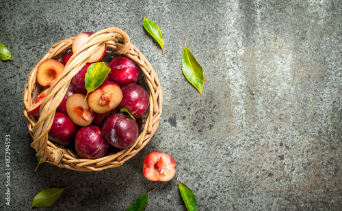 Fresh plums in a basket with leaves.
