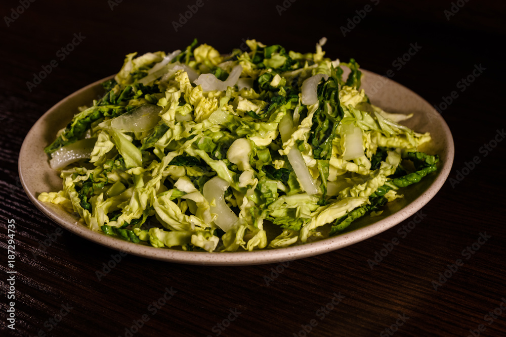 Salad with the savoy cabbage in the dish on dark wooden table