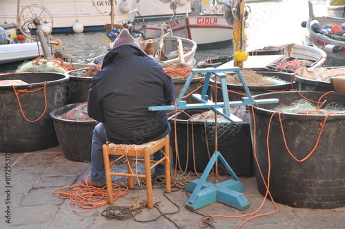 Fotografija fishermen repairing the fishing net in Camogli harbor, Genoa Province, Liguria,