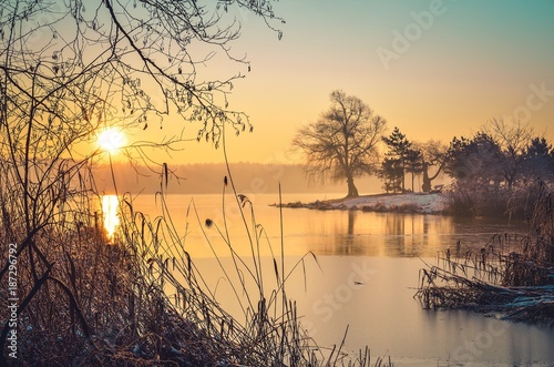 Beautiful winter landscape. Sunrise on the shore of the lake.
