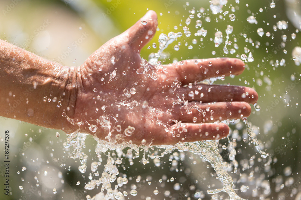 Fototapeta premium Hand of a man in a spray of water from a fountain