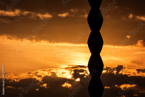 Beautiful sunset behind the silhouette of Endless Column sculpture by Brancusi