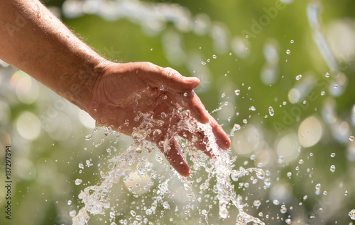 Hand of a man in a spray of water from a fountain