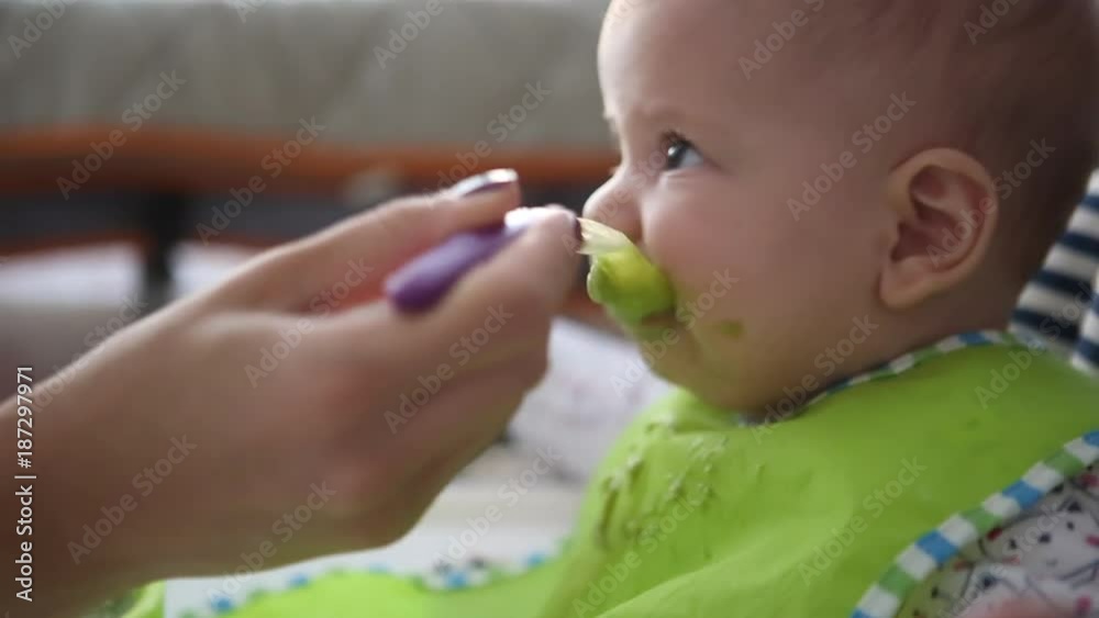 mother feeding six months old baby with spoon.close up mother feeding six months old baby with spoon.close up
